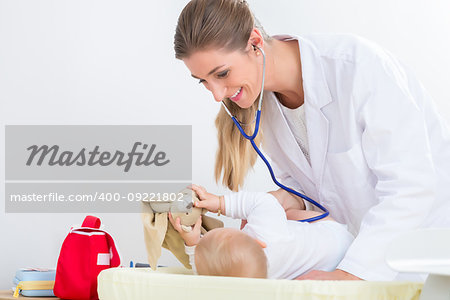 Dedicated female pediatrician using the stethoscope during the routine medical check-up of a cute and healthy baby girl in a modern healthcare center