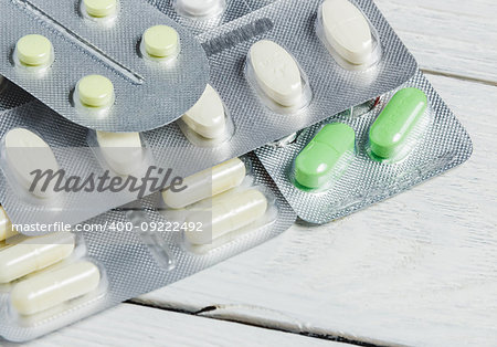 Set of Various Tablets and Capsules in Blisters on White Wooden Background with Copy Space. Medicine Concept