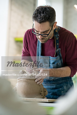 Ceramist Dressed in an Apron Sculpting Statue from Raw Clay in the Bright Ceramic Workshop.