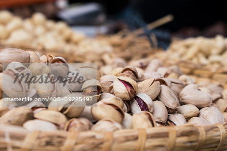 Background of basket of pistachios with shells, captured on street market, selective focus