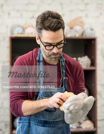 Portrait of Ceramist Dressed in an Apron Working on Clay Sculpture in the Bright Ceramic Workshop.