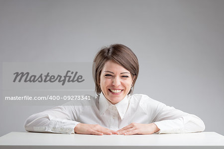 woman portrait in front of a table warmly laughing with lots of copyspace on a gray background