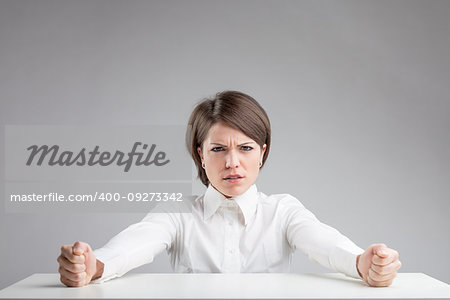 dislike concept on a woman's portrait over a gray background, she's clenching her punches