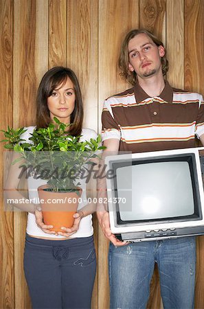 Woman Holding Plant And Man Holding Television
