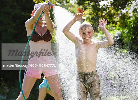 Mother Spraying Son With Hose