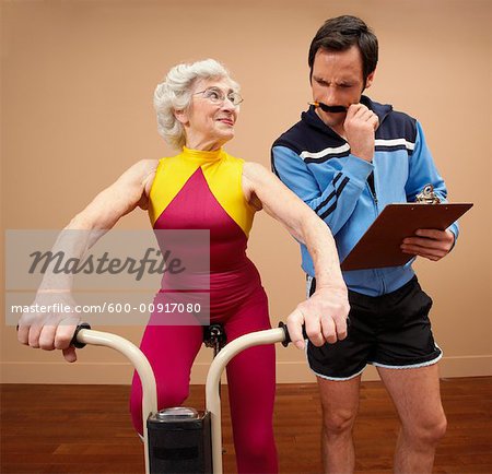 600-00917080em-personal-trainer-with-woman-on-exercise-bike-stock-photo.jpg