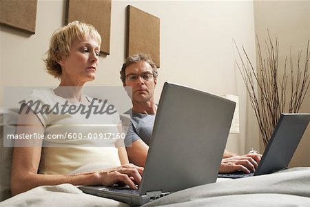 Couple with Laptops in Bed