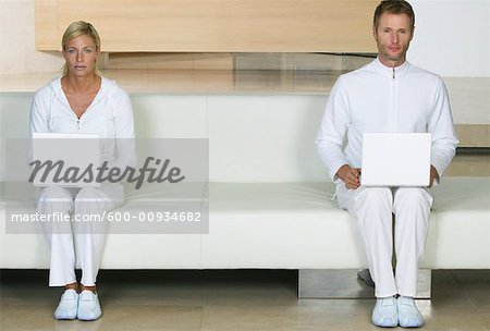 Portrait of Couple Sitting on sofa, Using Laptops