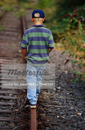 Boy Walking Along Train Tracks