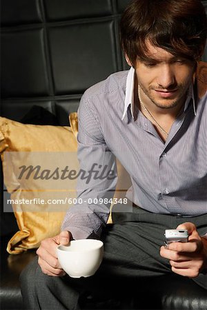 Businessman in Hotel Lobby with Cellular Phone and Coffee