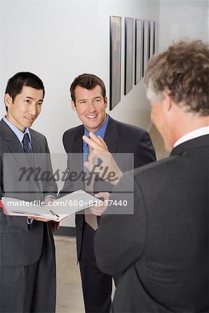 Businessmen Talking in Office Hallway