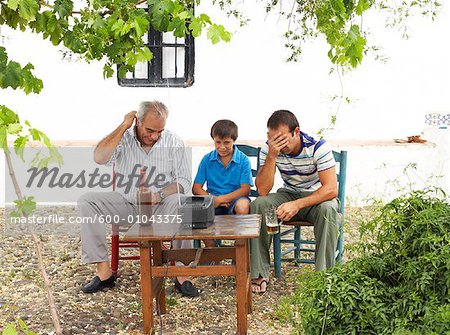 Grandfather, Father and Son Watching Television in Backyard