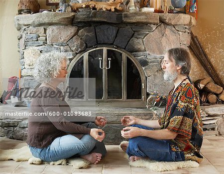 Hippie Couple Meditating in Front of Fireplace