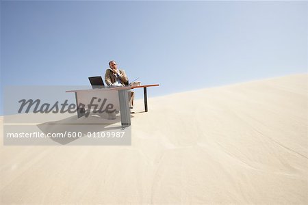 Businessman at Desk at Top of Sand Dune