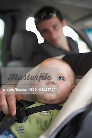 Father Adjusting Straps of Baby's Car Seat