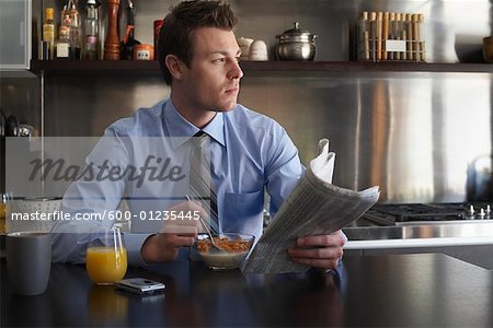 Man Reading Newspaper During Breakfast