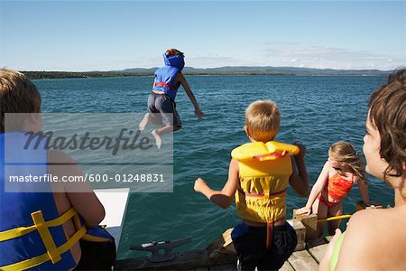 Children in Life Jackets Jumping Into Lake