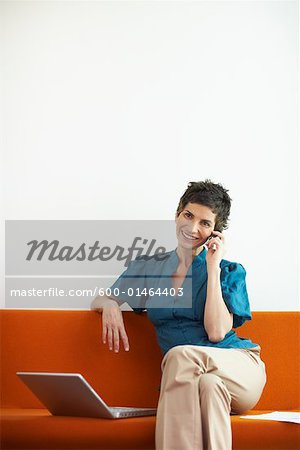 Woman with Cellular Phone and Laptop Computer on Sofa
