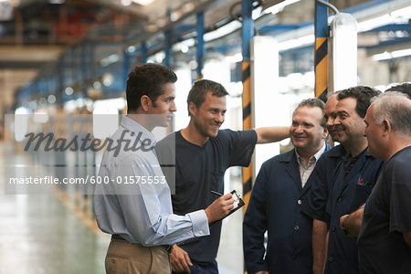 Man Talking to Workers in Automotive Plant