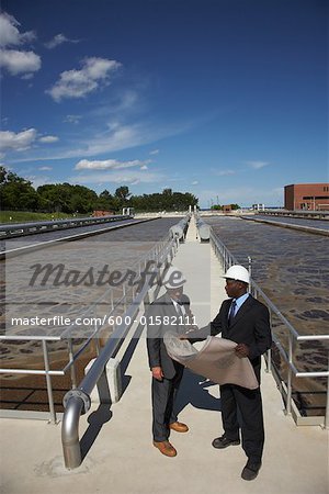 Businessmen Looking at Blueprint Outside Water Treatment Plant