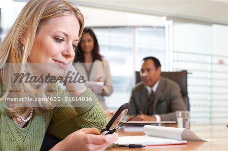 Businesswoman Using Cell Phone During Meeting