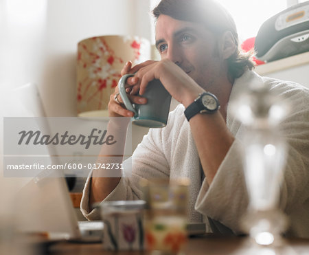 Portrait of Man Sitting in Front of Laptop Computer, Holding Mug