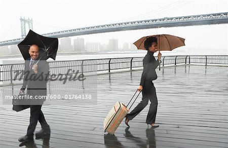 Business People Walking In Rain By Brooklyn Bridge New York City