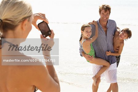 Woman Taking Picture of Husband with Children on Beach, Majorca, Spain