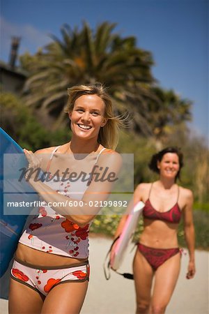 Two Young Women Carrying Surfboards