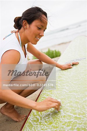 Woman Waxing Surfboard