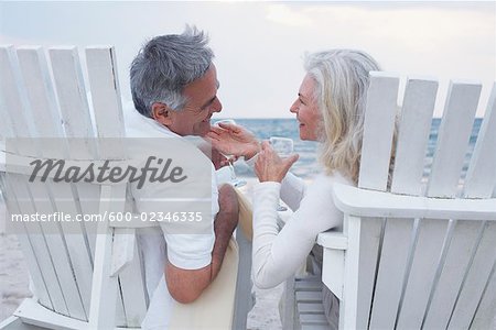 Couple with Wine Sitting in Chairs on Beach