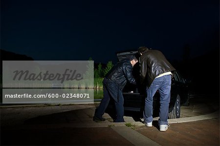 Men Removing Something From Car Trunk at Night