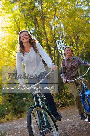 Two Women Riding Bicycles through Forest