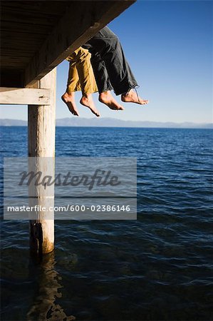 Women Dangling Feet from Dock over Lake