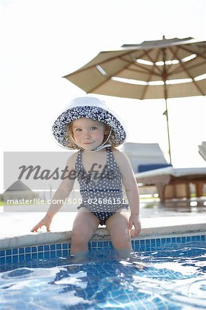 Girl Wearing Bathing Suit and Sunhat, sitting on Edge of Swimming Pool, Cancun, Mexico