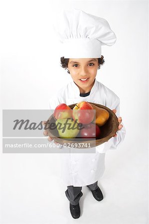 Boy Dressed Up as a Chef Holding Bowl of Fruit