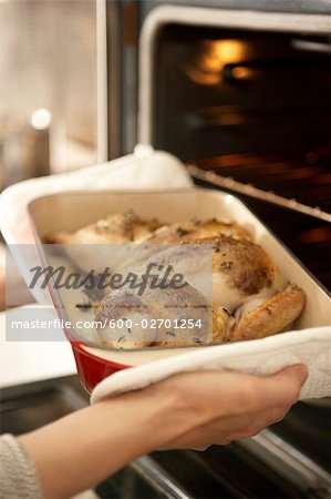 Woman Taking Roast Chicken out of Oven