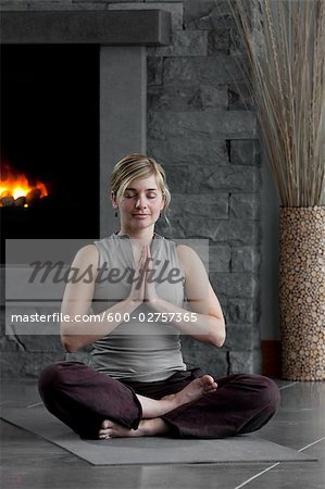 Woman Meditating at Home by the Fireplace