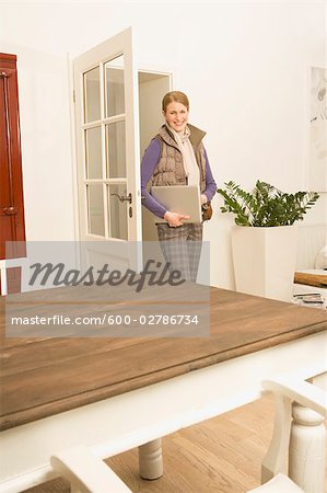 Woman Walking into Room Holding Laptop
