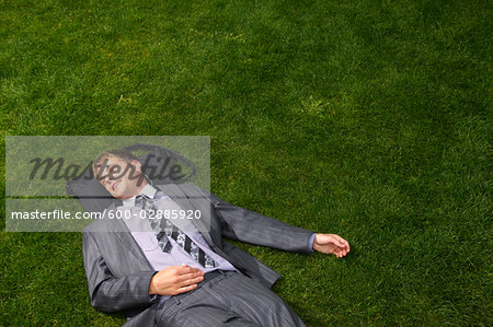 Businessman Lying on Grass Listening to Music Businessman Lying on Grass Listening to Music