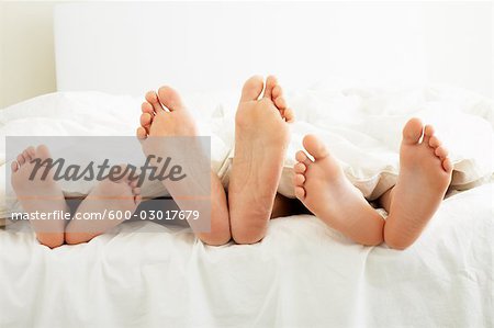 Close-up of Family's Feet in Bed