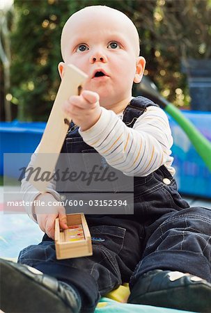 Boy Sitting in Backyard, Playing with Wooden Building Blocks