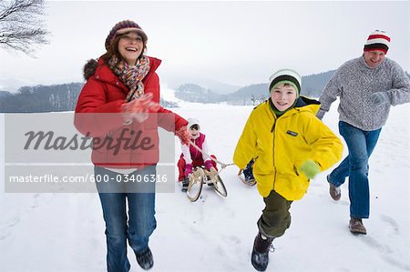 Parents and Brother Pulling Girl in Sled in Winter