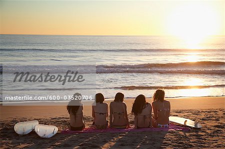 Backview of Young Women with Surfboards, Sitting on Beach watching Sunset, Zuma Beach, California, USA