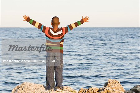 Boy on Rocks by Water