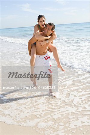 Man Giving Woman Piggyback Ride on Beach