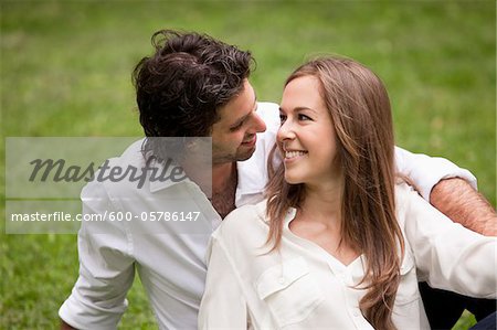 Close-up Portrait of Young Couple Sitting on Grass in Park