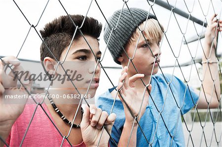 Two Boys Looking Through Chain Link Fence, Mannheim, Baden-Wurttemberg, Germany
