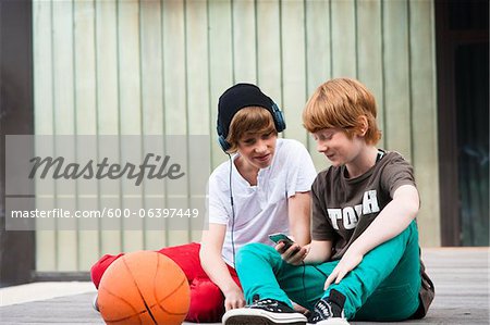 Boys using MP3 Player Outdoors, Mannheim, Baden-Wurttemberg, Germany