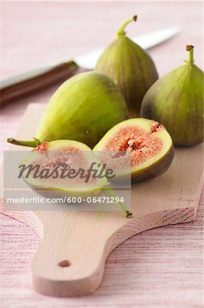 Close-up of Fresh Figs, One Cut in Half on Wooden Cutting Board on Pink Background